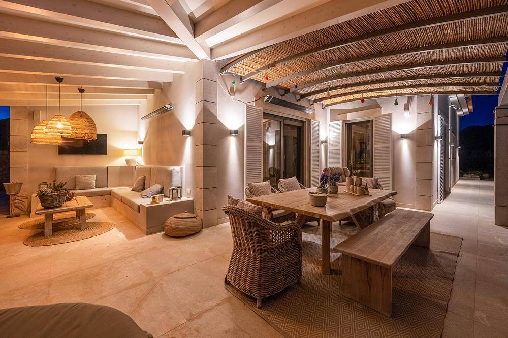 Stimmungsvoll beleuchtete überdachte Terrasse mit Ess- und Loungebereich für entspannte Abende.