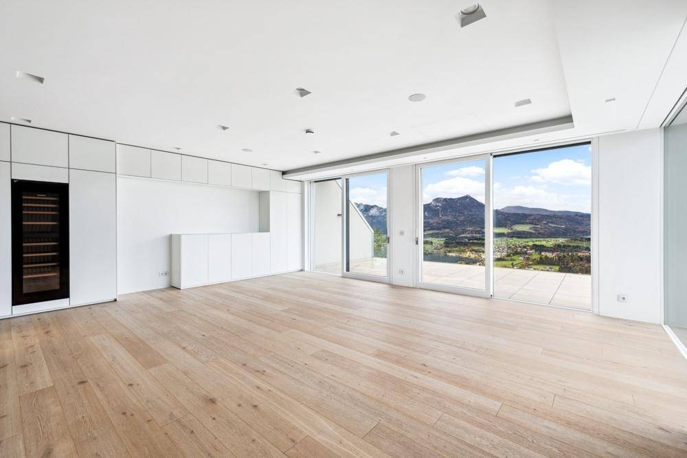 Heller, offener Wohnbereich mit Holzboden, integriertem Weinkühlschrank und Panoramablick auf die Berge.