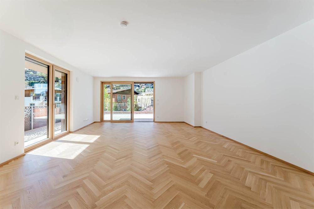 Helles und geräumiges Wohnzimmer mit Fischgrätparkett und großen Fenstern zum Balkon.