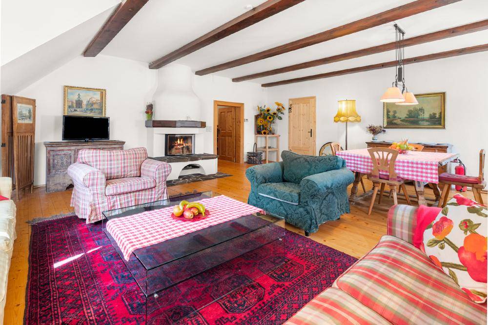 Helles Wohnzimmer mit Holzdielenboden, sichtbaren Deckenbalken und einem einladenden Kamin.