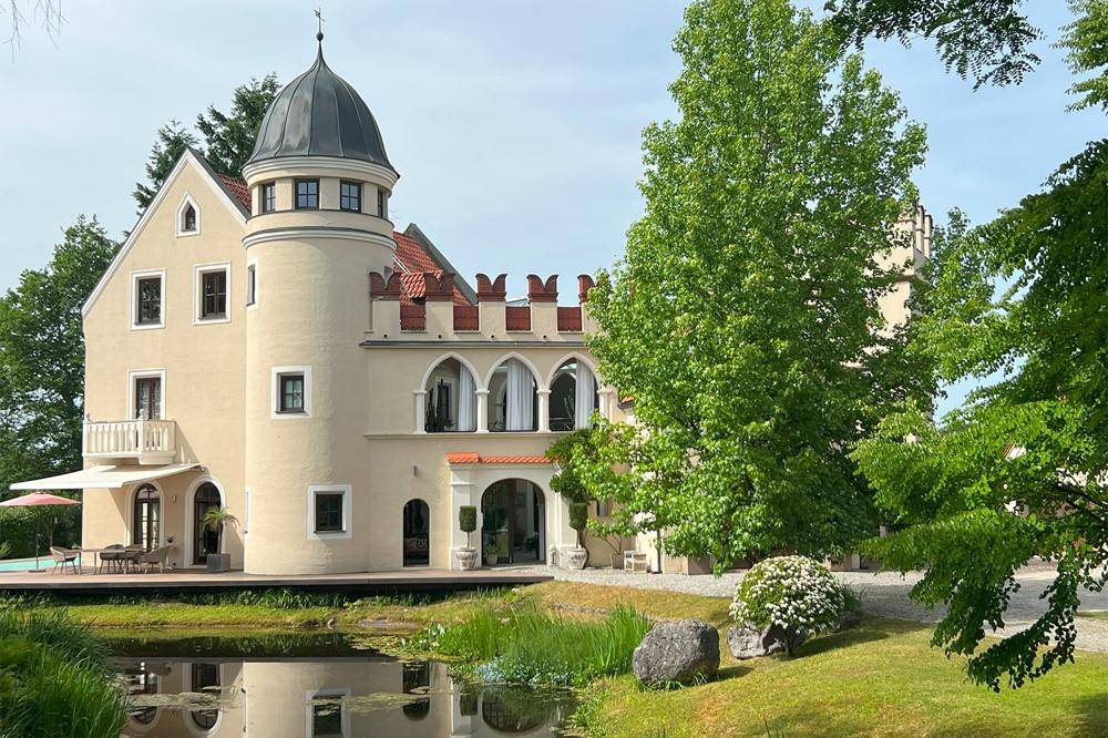 Detailansicht des historischen Anwesens mit markantem Turm und dekorativen Fassadenelementen.