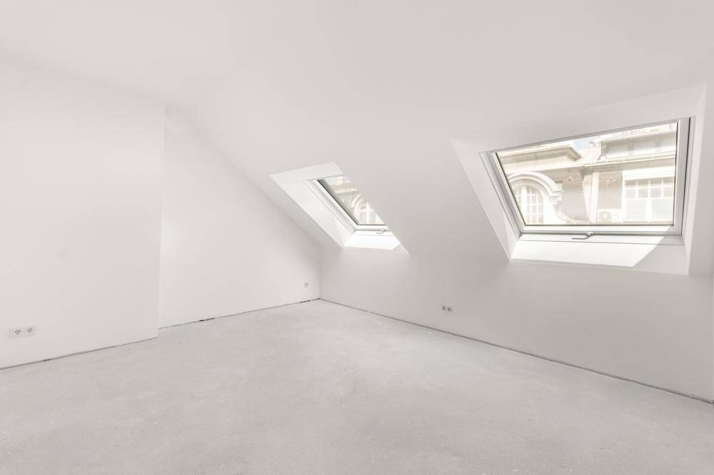 Helles, modern eingerichtetes Wohnzimmer mit großen Fenstern, Stadtblick und elegantem Fischgrätparkett.