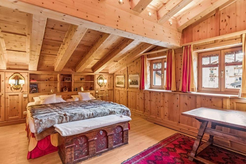 Dachgeschoss-Schlafzimmer mit sichtbaren Holzbalken, Holzvertäfelung und gemütlichem Doppelbett.