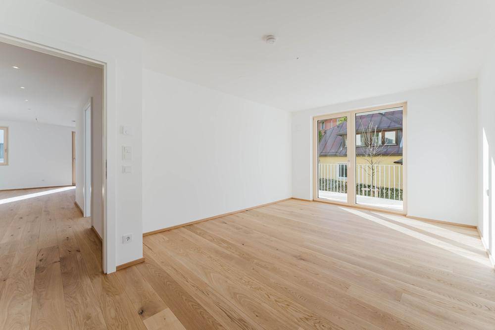Lichtdurchfluteter Raum mit Holzboden und Zugang zu einem französischen Balkon, ideal für Wohn- oder Schlafbereich.