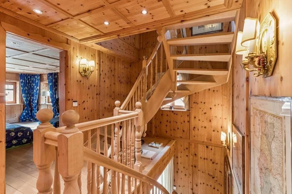 Helles Treppenhaus mit Holzgeländer und Wandvertäfelung, das verschiedene Ebenen verbindet.
