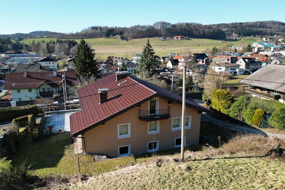 Luftaufnahme des Einfamilienhauses mit rotem Dach und weitem Blick über die ländliche Umgebung.
