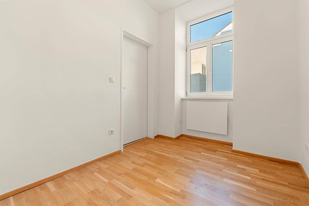 Lichtdurchflutetes Zimmer mit Parkettboden und einem Fenster, vielseitig nutzbar als Schlaf- oder Arbeitszimmer.