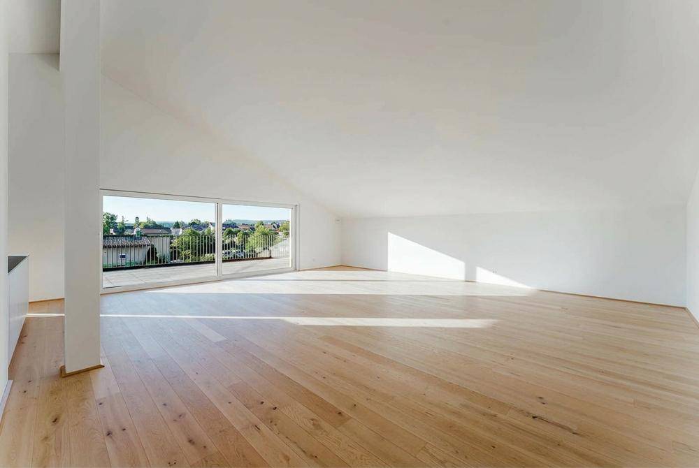 Lichtdurchfluteter Wohnraum mit Holzboden und weitem Ausblick durch große Fenster.