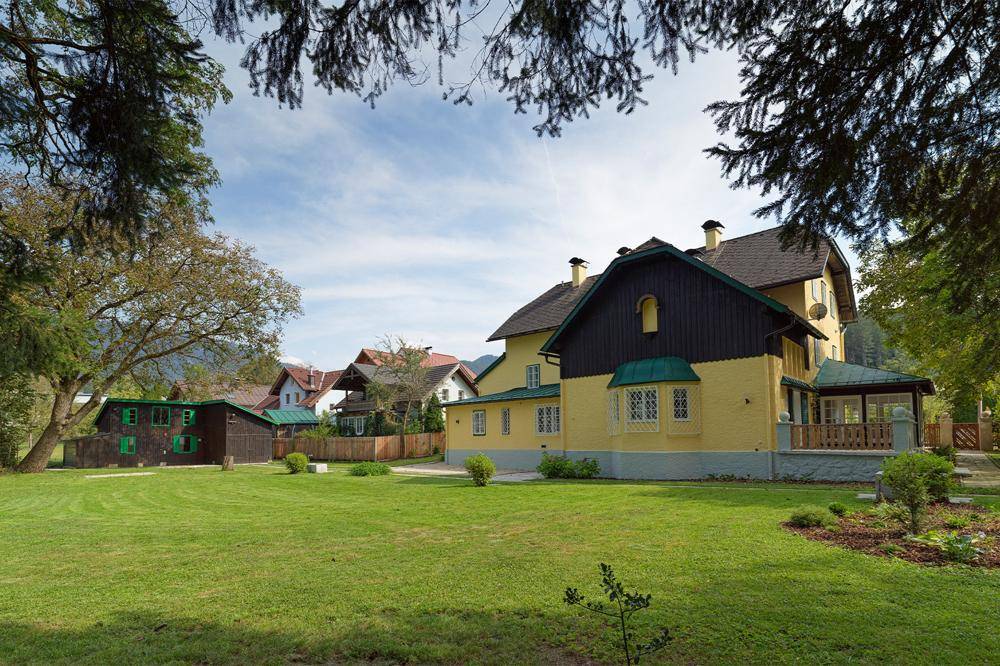 Weitläufige Rasenfläche vor dem Landhaus mit Blick auf die umliegende Landschaft.