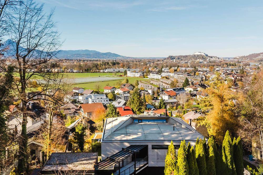 Panoramablick auf die moderne Immobilie und die umliegende Wohngegend mit viel Grün.