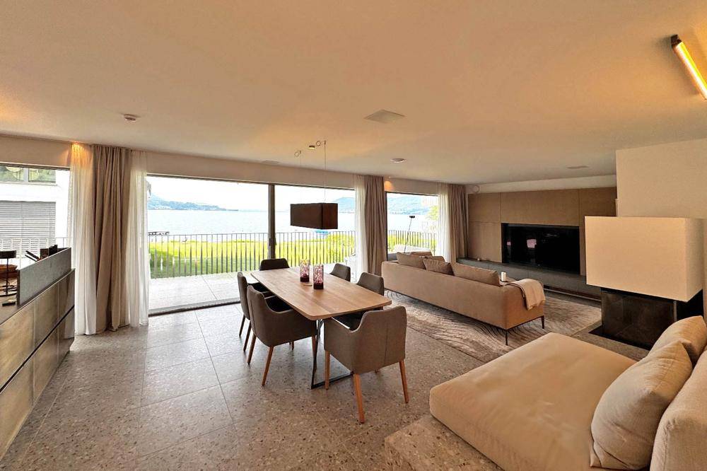 Geräumiger Wohn- und Essbereich mit großen Fenstern, Seeblick und modernem Design.