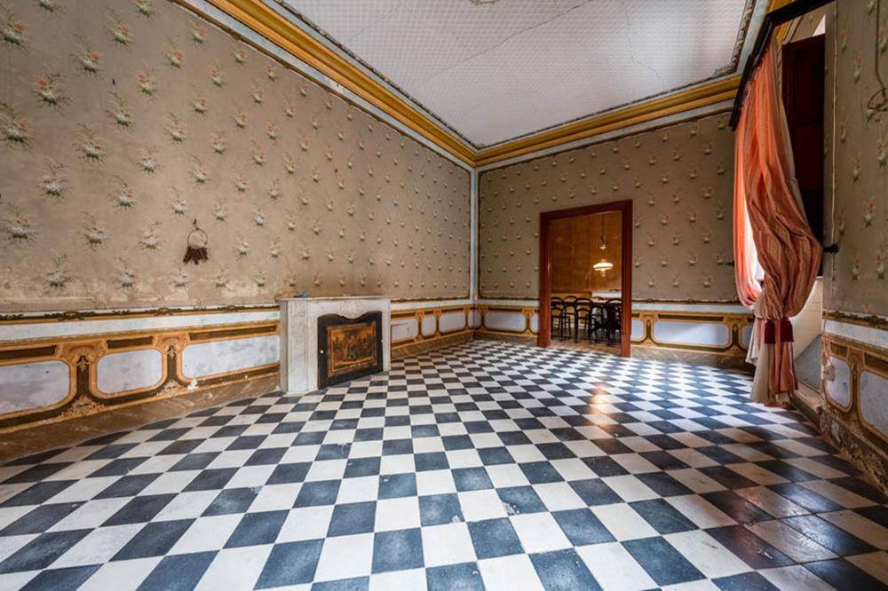 Geräumiger Raum mit auffälligem Schachbrett-Fliesenboden und historischer Wanddekoration.
