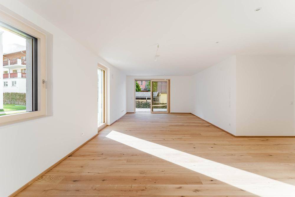 Heller Wohnbereich mit Holzboden und Zugang zu einem Balkon, der viel Sonnenlicht bietet.