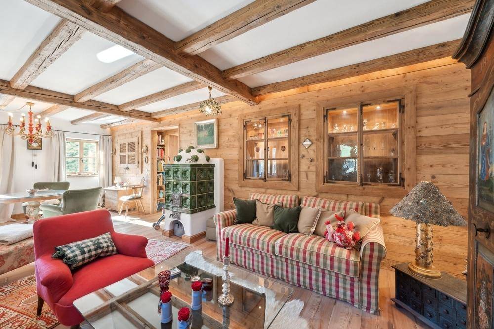 Rustikales Wohnzimmer mit Holzbalken, Kachelofen und gemütlichen Sitzgelegenheiten im Landhausstil.