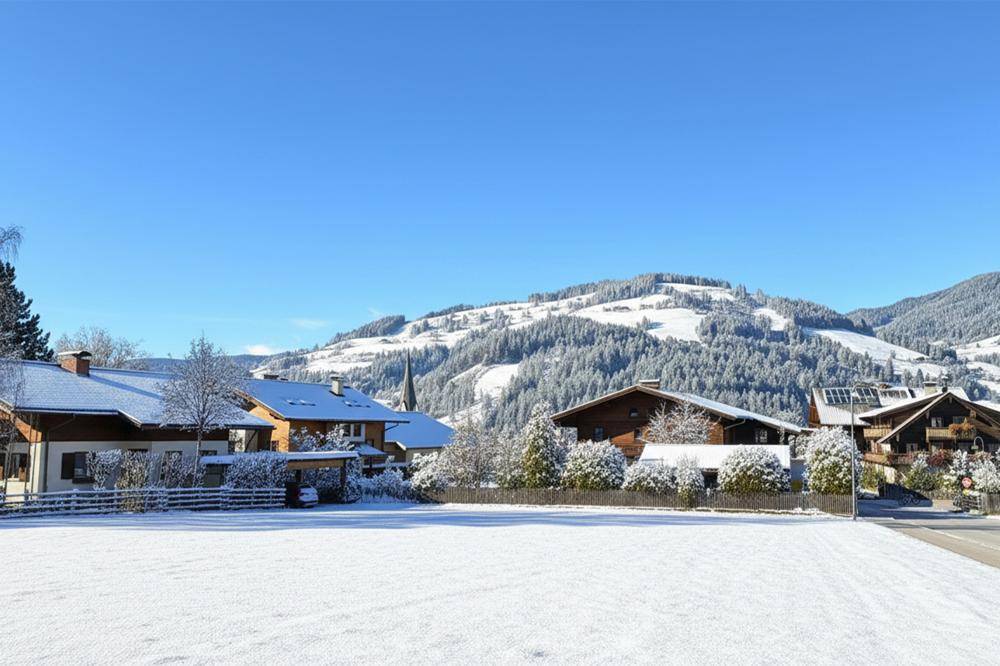 Winterliche Landschaft mit verschneiten Häusern und Bergen unter strahlend blauem Himmel.