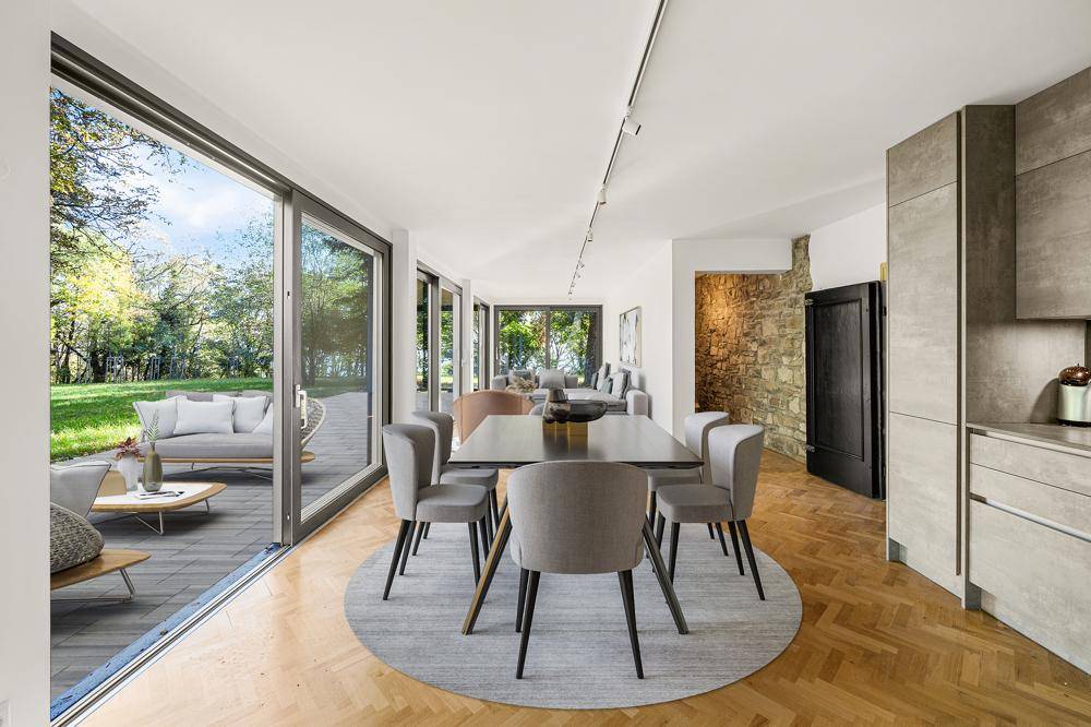 Moderner Essbereich mit großen Glasfronten, die den Blick auf die Terrasse und den Garten freigeben.