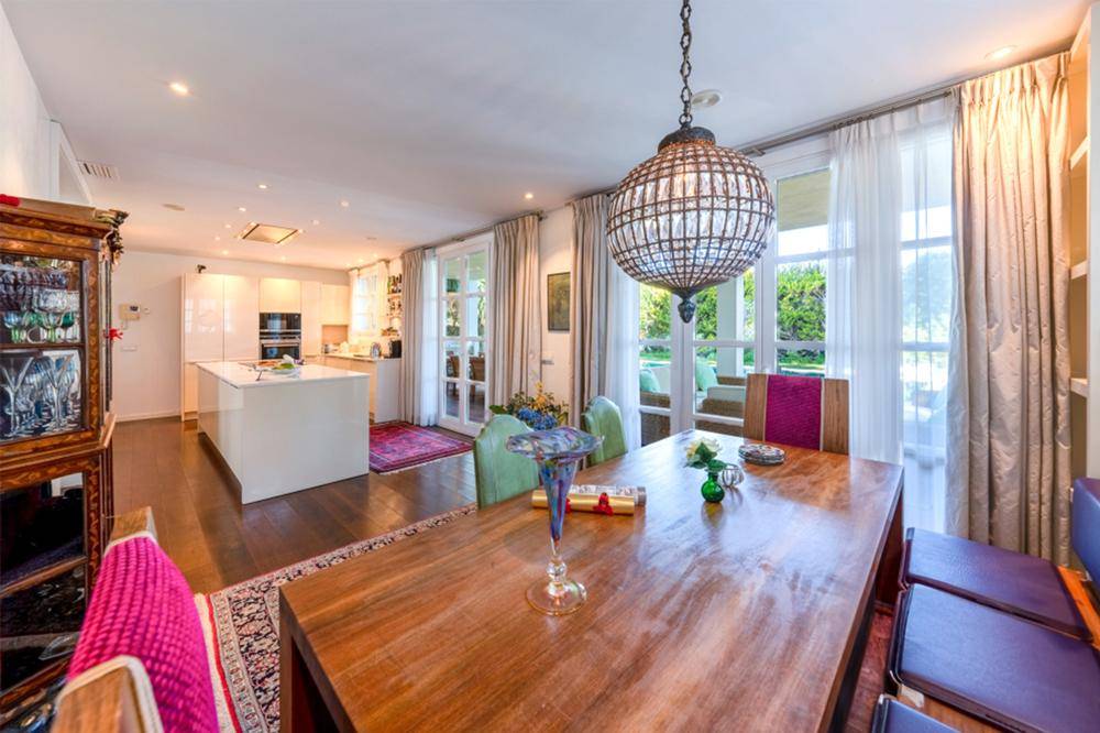 Eleganter Essbereich mit Holztisch und farbigen Stühlen, offen zur modernen Küche und mit viel Tageslicht.