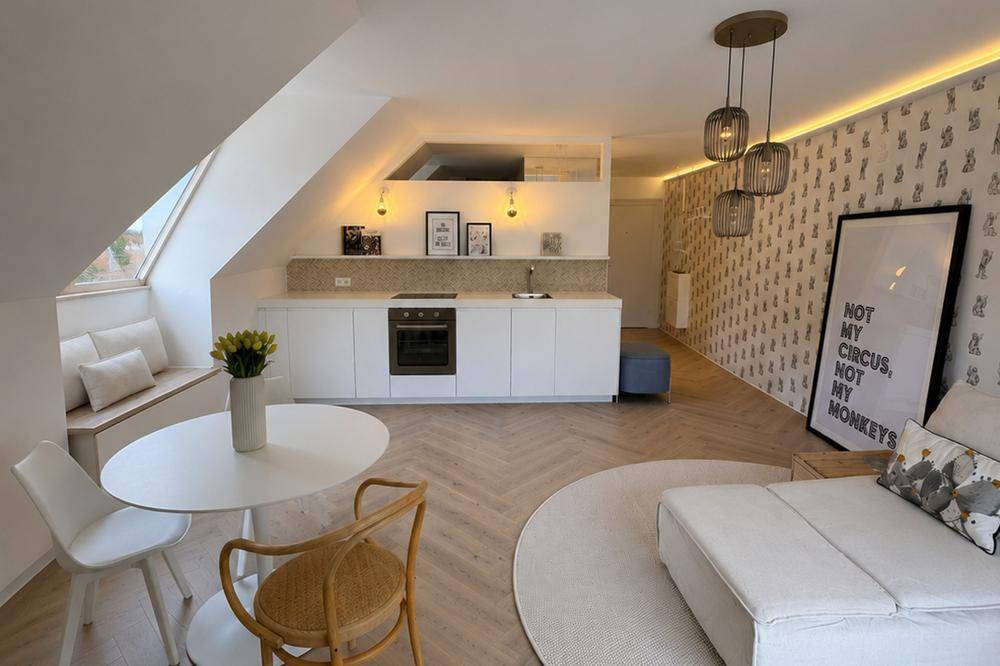 Helles, offenes Dachgeschoss-Apartment mit integrierter Küche, Essbereich und gemütlicher Sitzecke unter der Dachschräge.