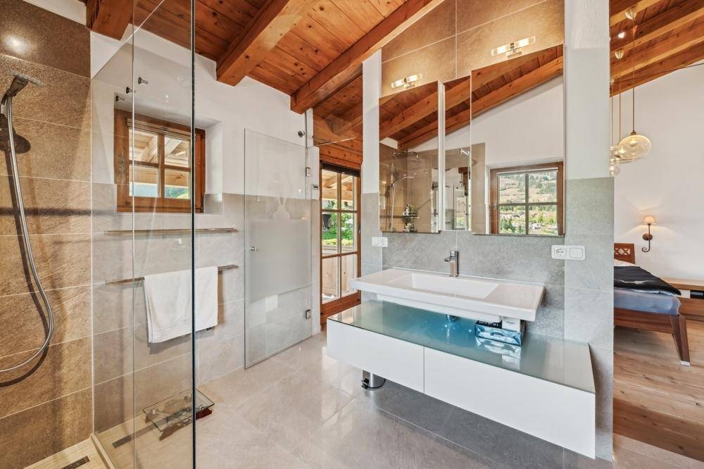 Modernes Badezimmer mit begehbarer Dusche, Doppelwaschbecken und Holzbalkendecke.