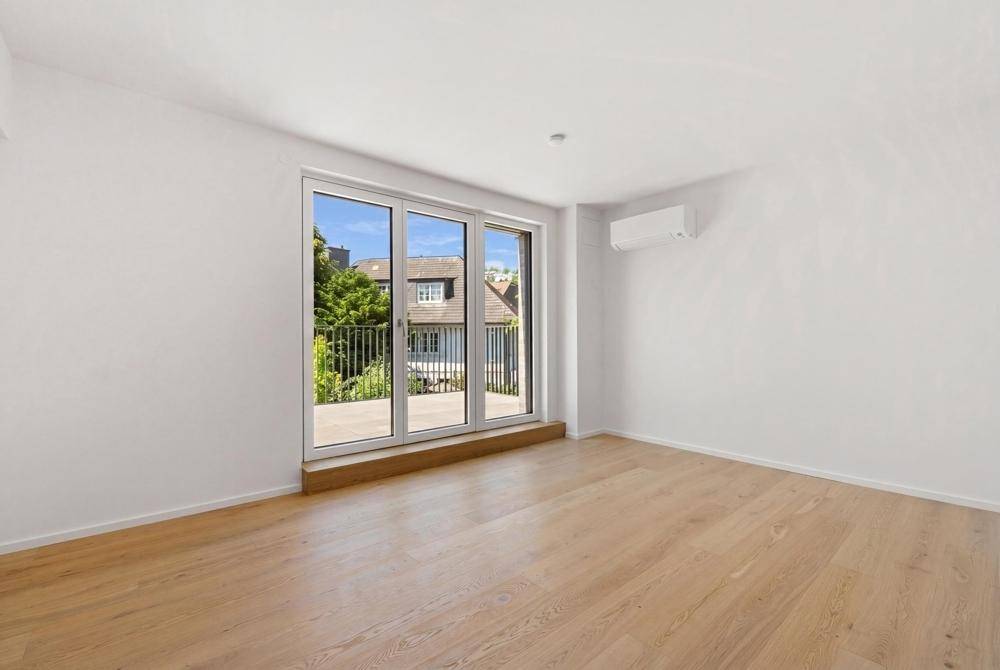 Helles Zimmer mit Parkettboden, Klimaanlage und Zugang zu einem Balkon.
