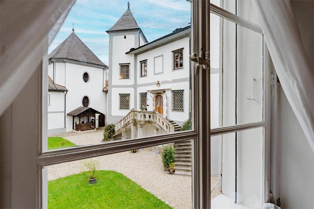 Blick aus einem Fenster auf den gepflegten Innenhof und die historische Fassade mit der Freitreppe.