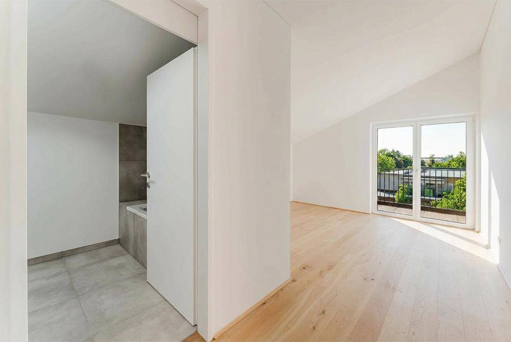 Heller Flurbereich mit Zugang zu einem Badezimmer und einem Zimmer mit Balkon.