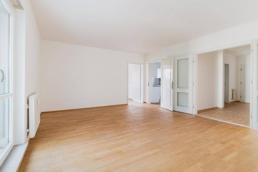 Geräumiges, leeres Zimmer mit hellem Parkettboden und weißen Wänden, bereit zur individuellen Gestaltung.