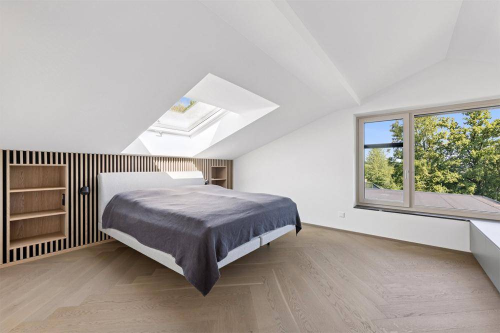 Helles Schlafzimmer im Dachgeschoss mit Dachfenster, Holzakzenten und Parkettboden.