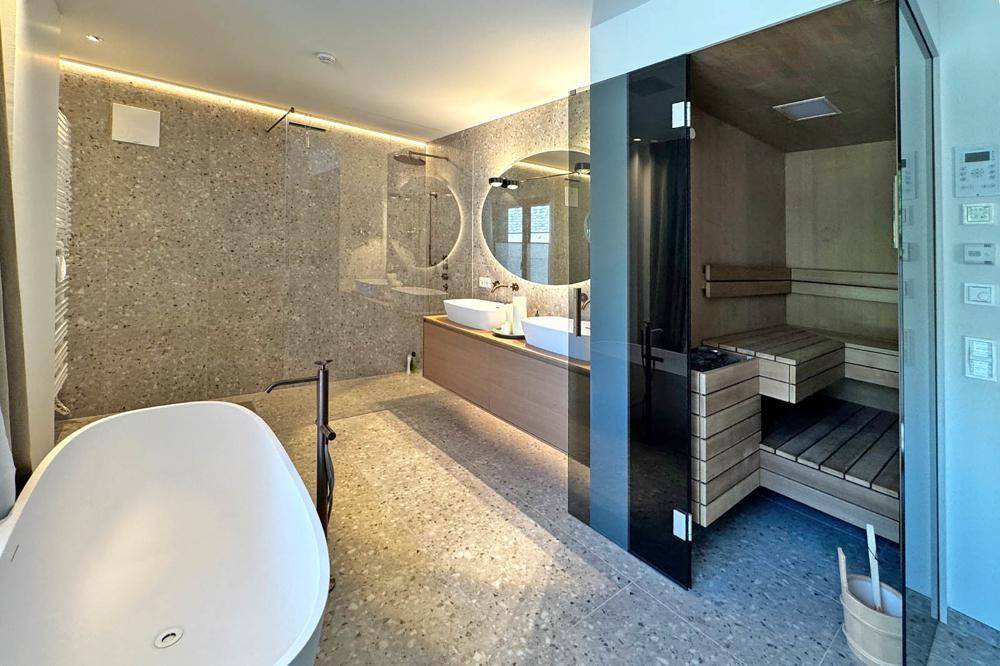 Luxuriöses Badezimmer mit freistehender Badewanne, Doppelwaschbecken und integrierter Sauna.