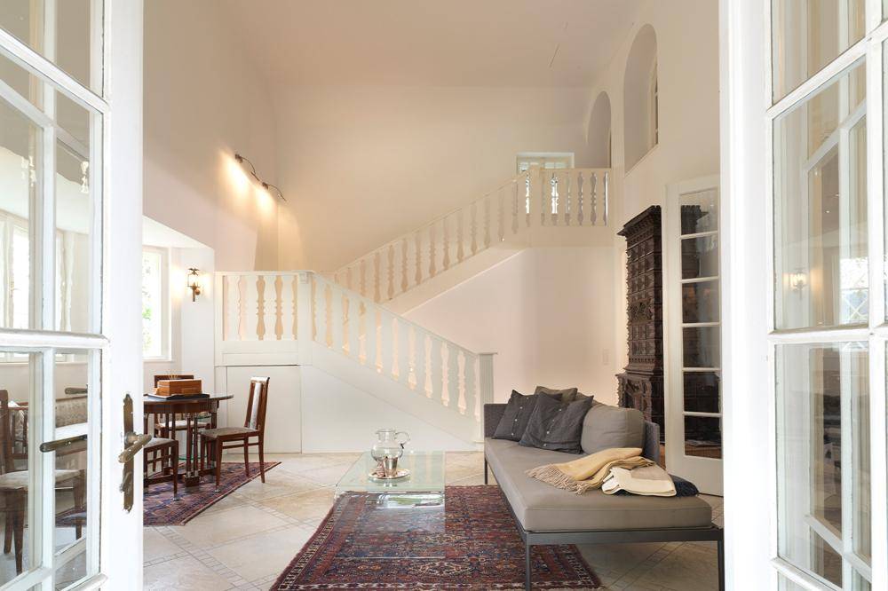 Eleganter Wohnbereich mit geschwungener Treppe, hohen Decken und hellem Ambiente.