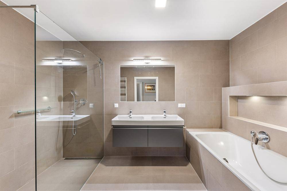 Das stilvolle Badezimmer mit Regendusche und Badewanne
