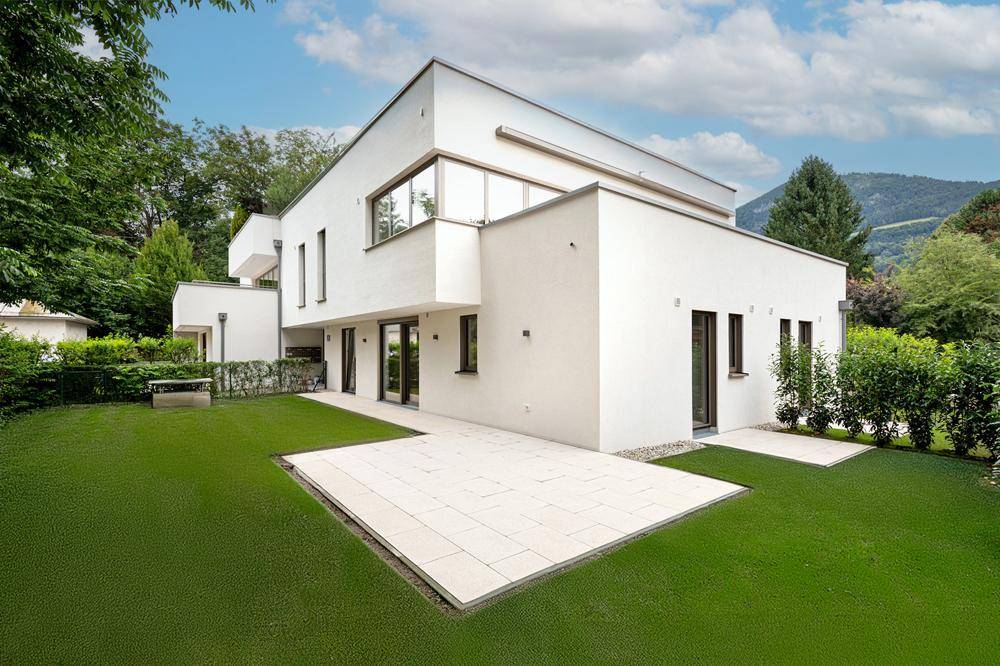 Moderne Villa mit großer Terrasse und weitläufigem Gartenbereich in grüner Umgebung.