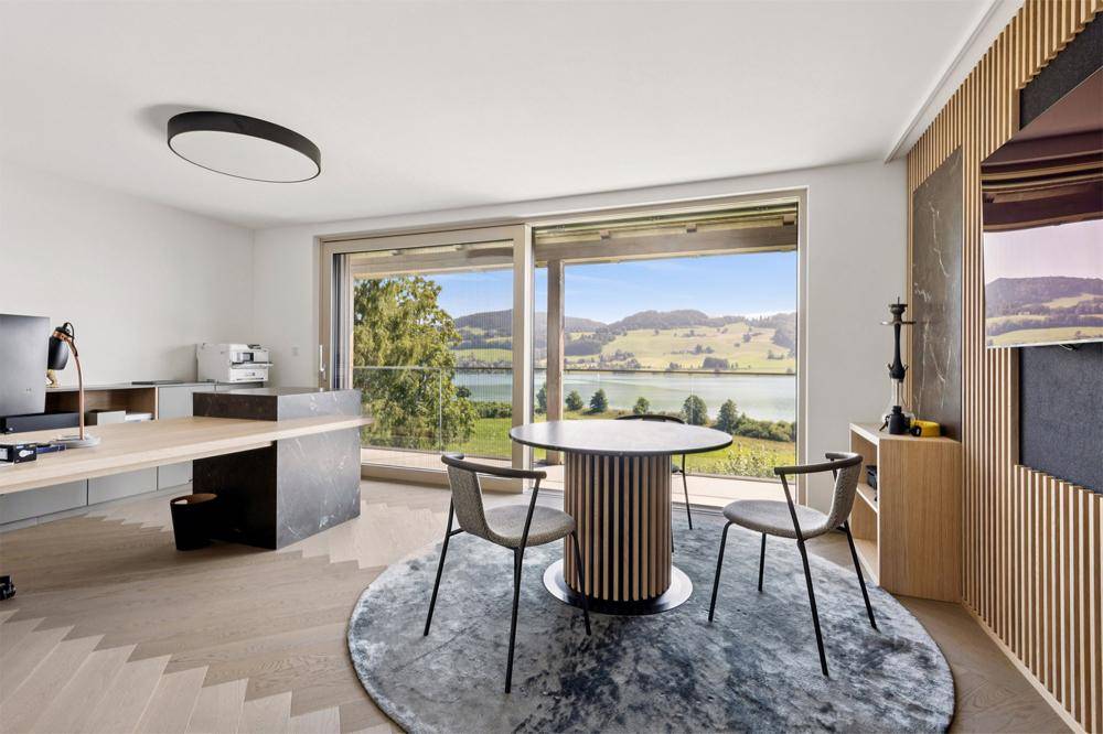 Helles Arbeitszimmer mit modernem Schreibtisch, Holzakzenten und weitem Seeblick.