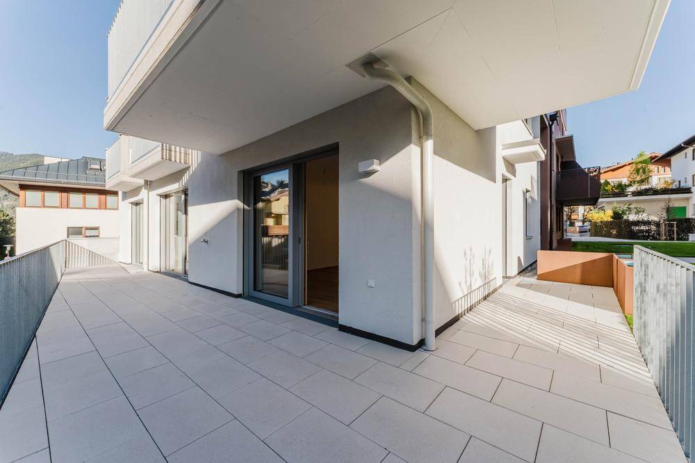 Große, geflieste Terrasse mit Metallgeländer und Blick auf die umliegende Bebauung.