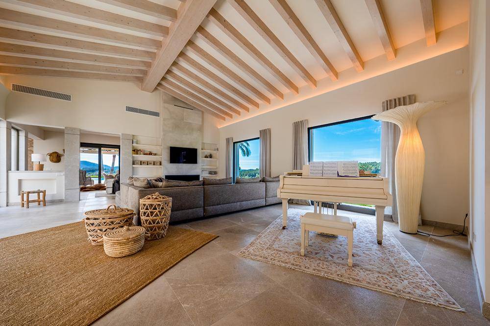 Geräumiges Wohnzimmer mit hohen Decken, sichtbaren Holzbalken und einem eleganten Flügel.