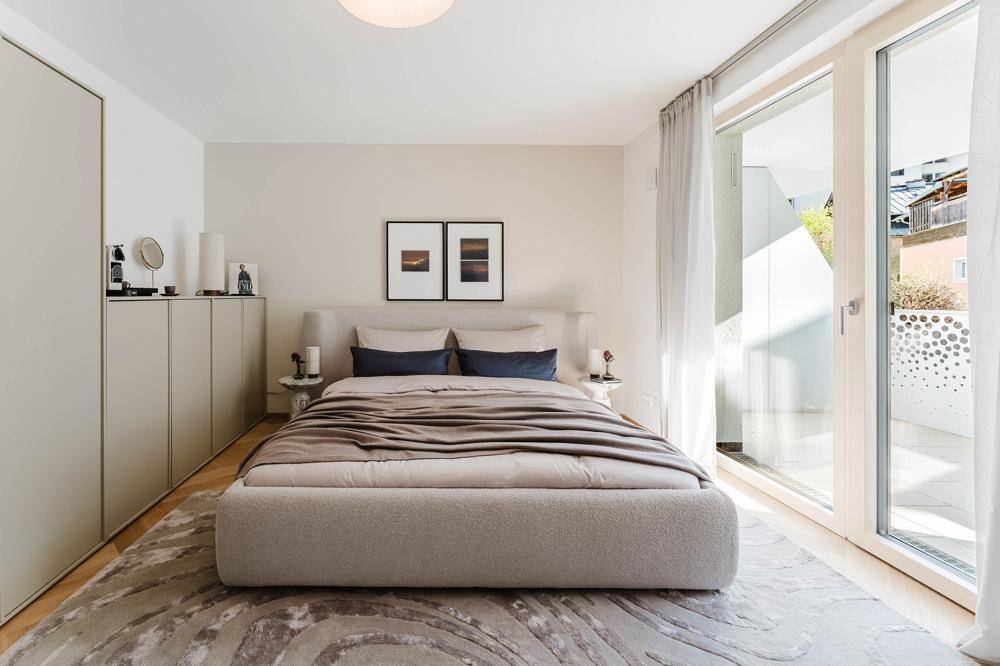 Helles Schlafzimmer mit Doppelbett, Einbauschränken und Zugang zum Balkon.