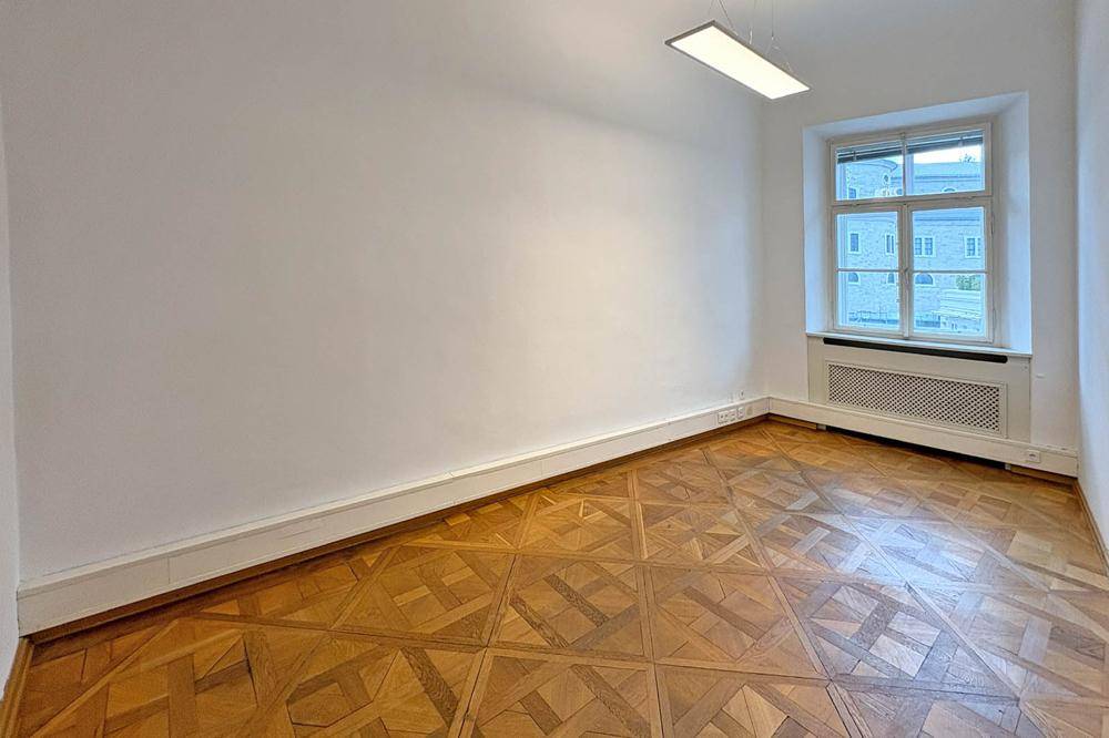 Helles Zimmer mit einzigartigem Parkettboden und einem großen Fenster.