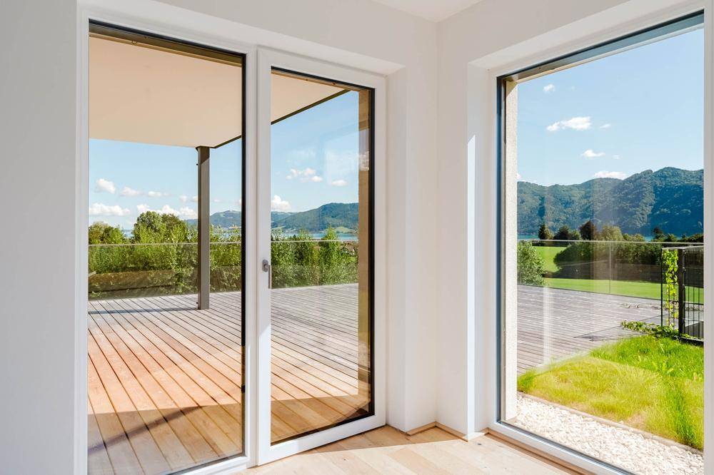 Große Fenster und Schiebetüren bieten einen weiten Blick auf die umliegende Natur und den See.