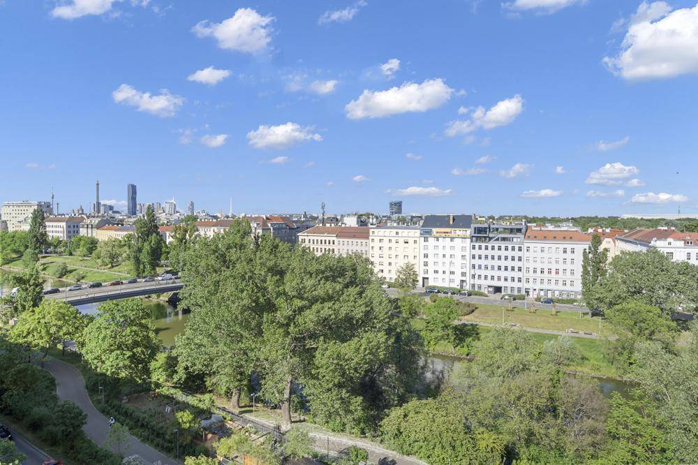 Panoramablick über die Stadt mit Fluss, grünen Ufern und urbaner Architektur.