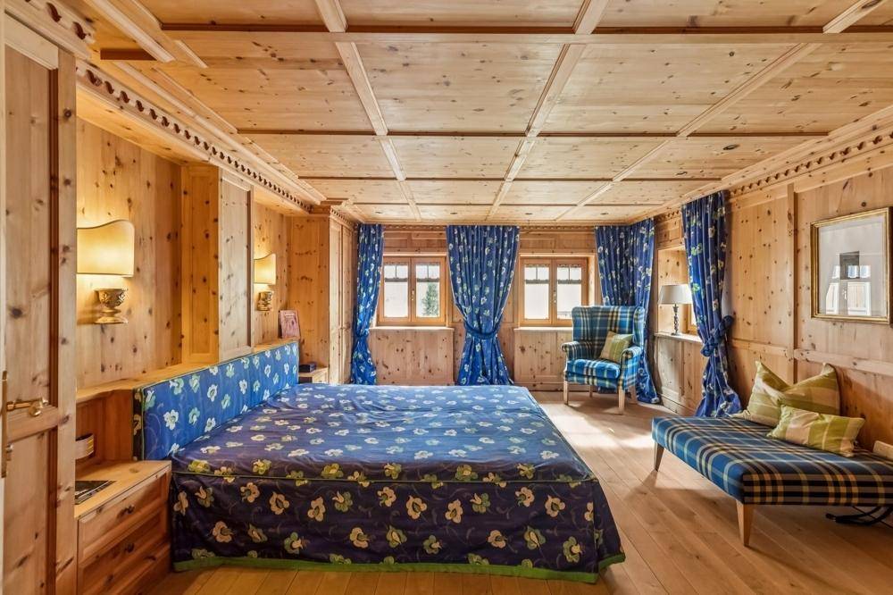 Geräumiges Schlafzimmer mit Holzvertäfelung, großem Bett und blauen Vorhängen im Landhausstil.