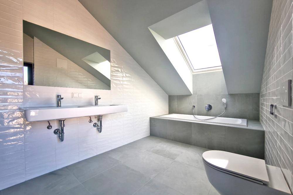 Modernes Badezimmer im Dachgeschoss mit Dachfenster, Doppelwaschbecken und integrierter Badewanne.