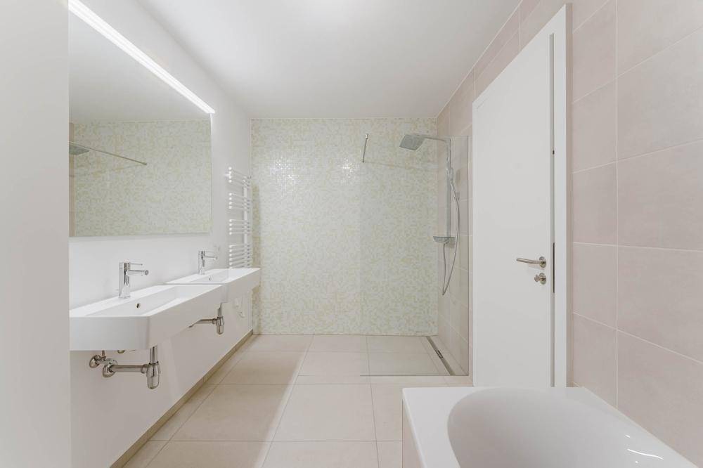 Modernes Badezimmer mit Doppelwaschbecken, begehbarer Dusche und Badewanne.