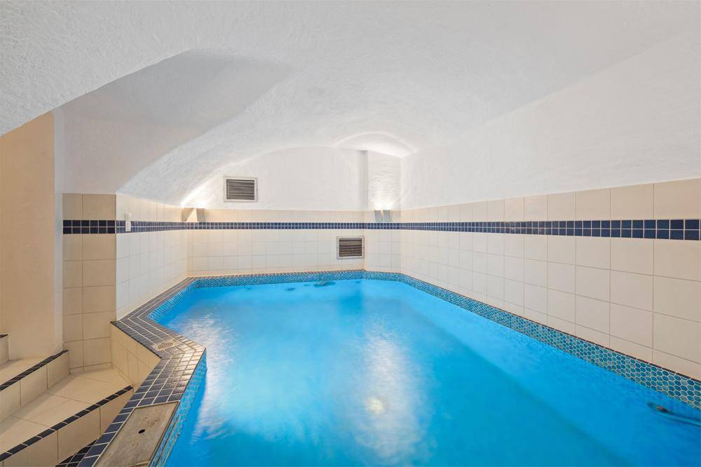 Innenpool mit blauen Fliesen und gewölbter Decke, Teil eines privaten Wellnessbereichs.