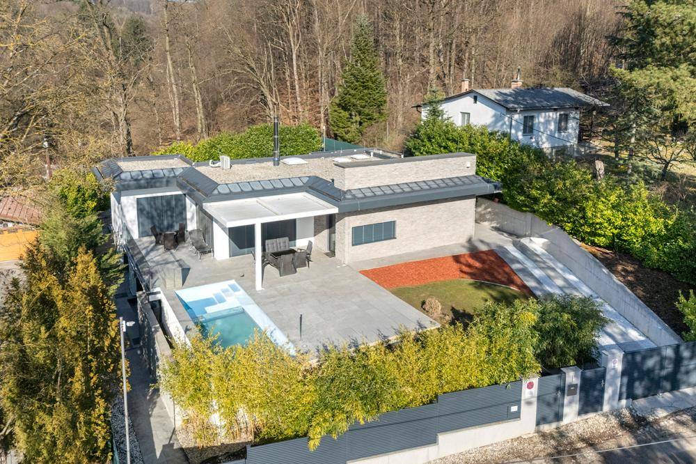 Luftaufnahme der modernen Villa mit Poolbereich und umliegender grüner Landschaft.