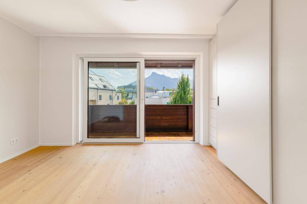 Helles Schlafzimmer mit Holzboden, Einbauschrank und Bergblick vom Balkon.