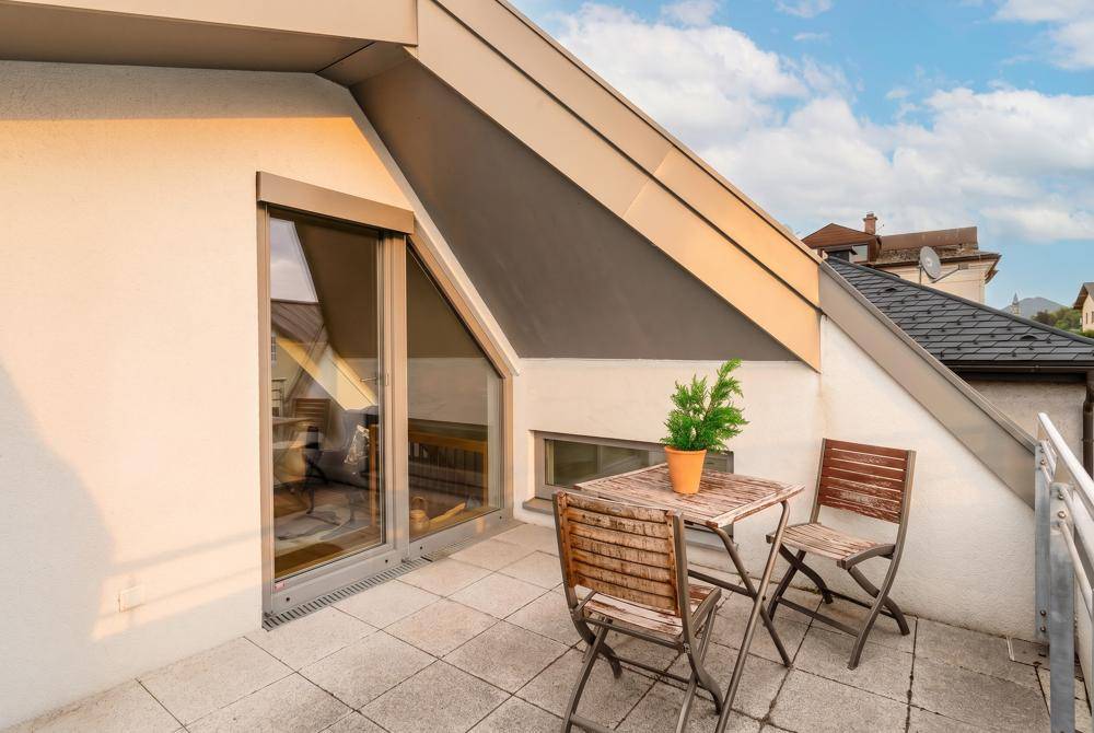 Sonniger Terrassenbereich mit kleinem Holztisch und Stühlen, ideal für entspannte Stunden im Freien.