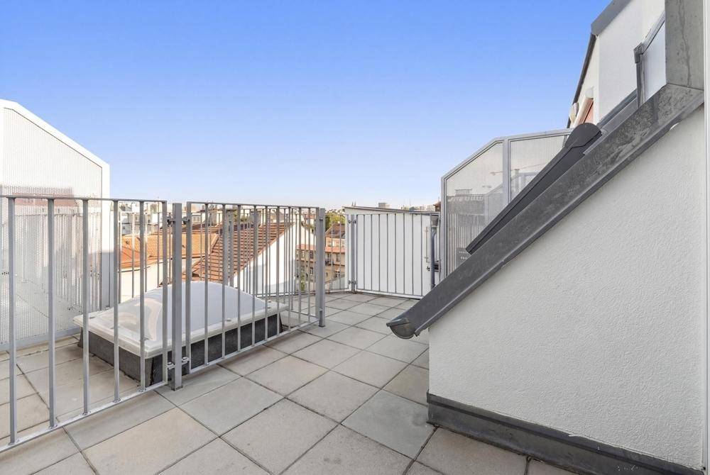 Geräumige Dachterrasse mit Fliesenboden, Metallgeländer und einem integrierten Whirlpool.