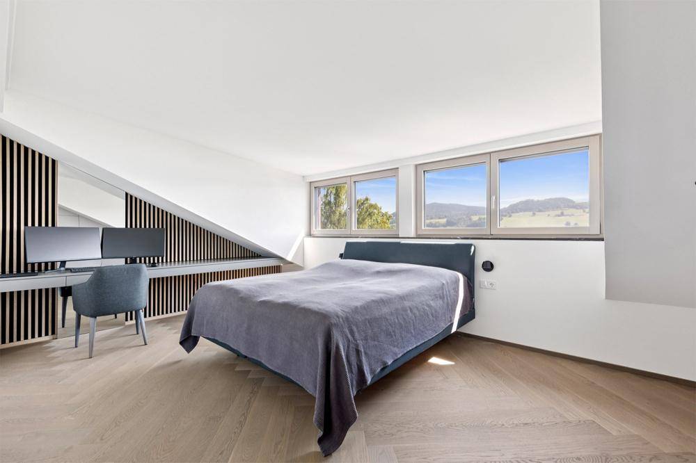 Schlafzimmer mit integriertem Arbeitsbereich, Holzwandverkleidung und weitem Landschaftsblick.