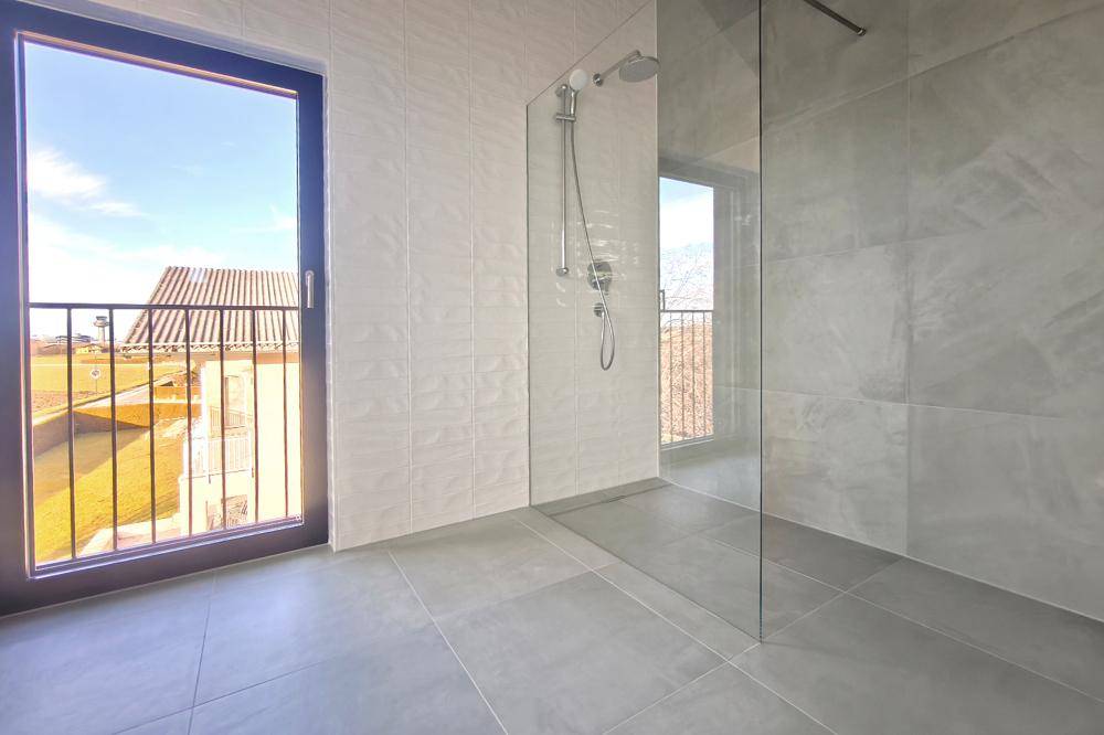 Modernes Badezimmer mit großer begehbarer Dusche und französischem Balkon für Tageslicht.