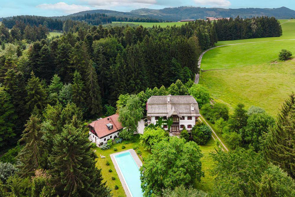 Weitläufiges Anwesen mit Haupthaus, Nebengebäude, Pool und großem Garten, eingebettet in eine Waldlandschaft.